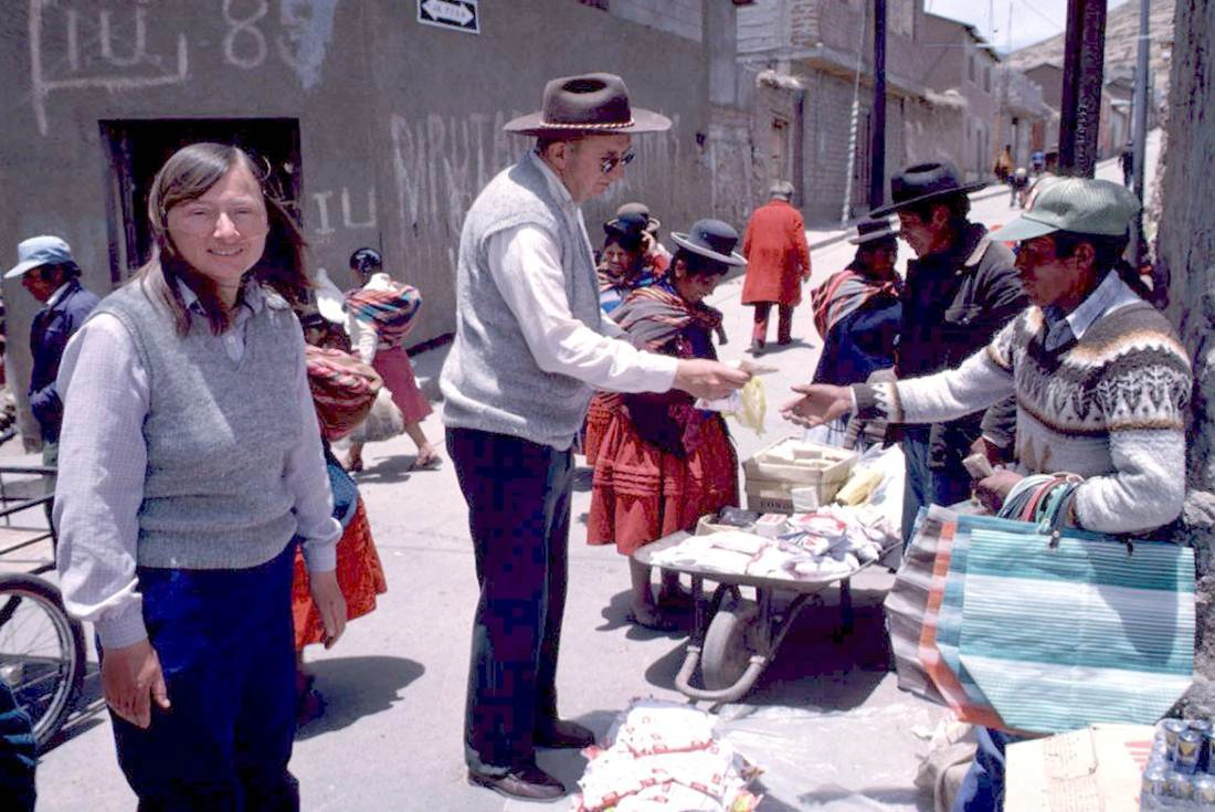 Carolyn looks on as Bosse pays a merchant at a market in Peru