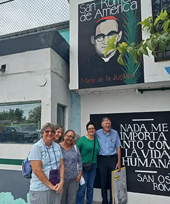 Maryknollers Debbie & Heidi stand with others outside of the Casa Oscar Romero building.