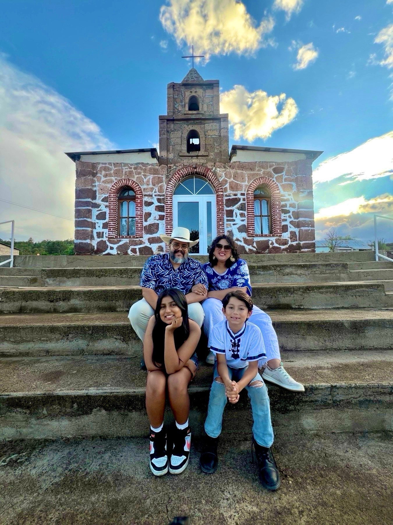 Maryknoll Lay Missioner, Gaby Hernandez, stands in front of the American, Bolivia, Vatican, and El Salvador flags signifying her connection to MKLM in America, her home nation of El Salvador, the Catholic connection from the Vatican, and her place of mission in Bolivia.