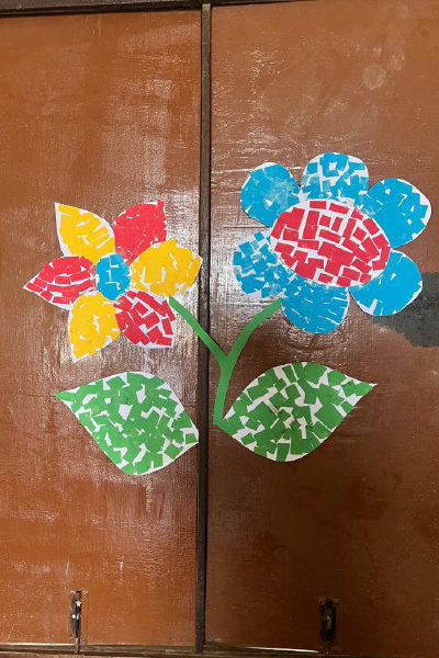 Tiny squares of cut colored paper form a flower like a stained glass window.