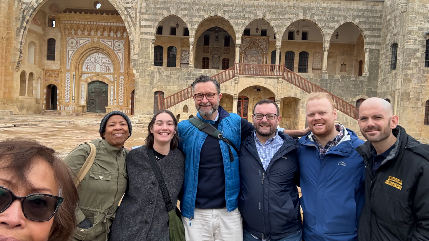 7 individuals pose for a selfie photo in front of a Church building.