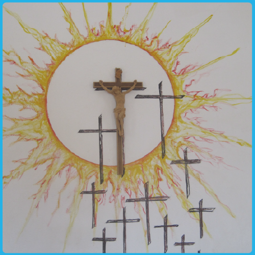 A crucifix is surrounded by a circle and rays like the sun. Several additional crosses are painted on the wall below the crucifix.