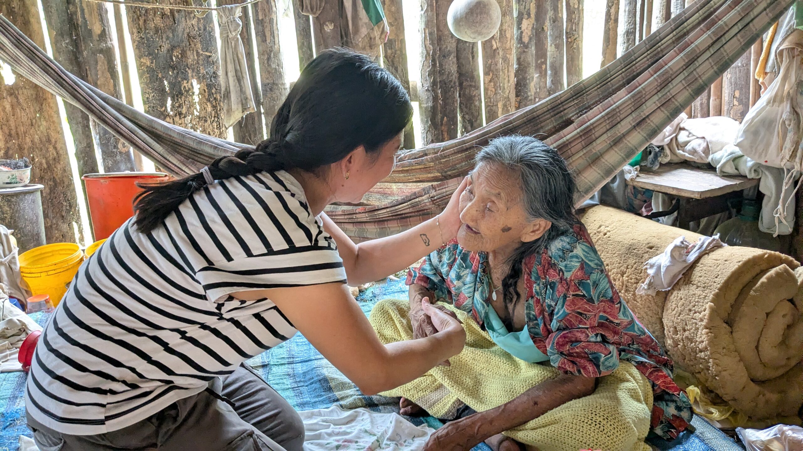 MKLM Gaby Hernandez presses her hand to an elderly woman's face in a caring matter.