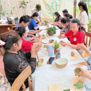 An image of mostly Cambodian women at a table forming pottery.