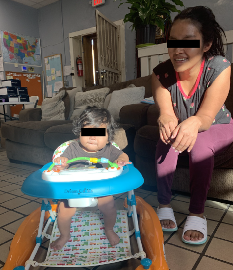A mother smiles watching her baby in the walker.