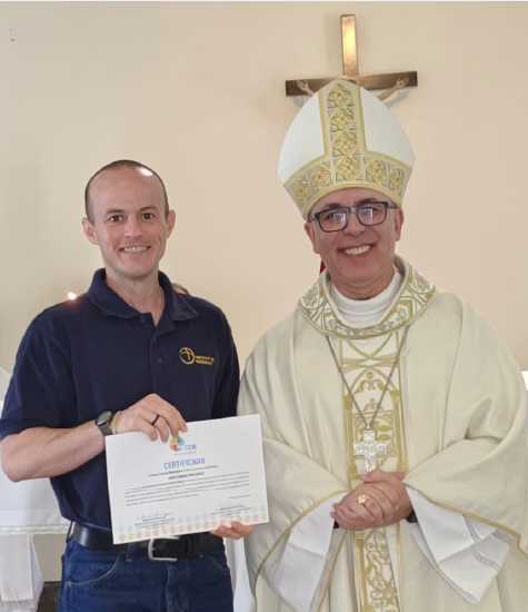 Maryknoll Lay Missioner James Pawlowicz stands next to a Bishop wearing his miter.