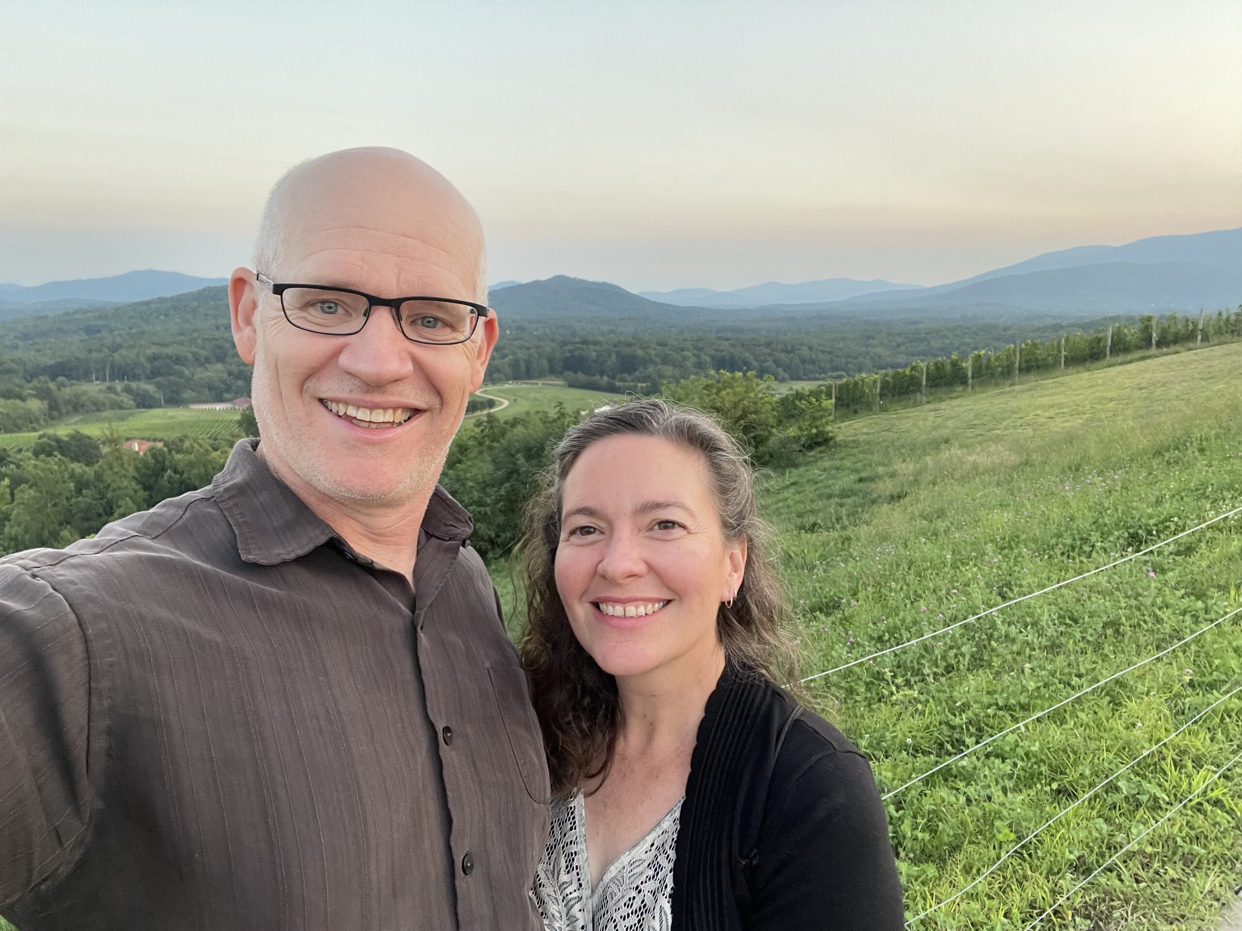 Steve and Laura Brown pose together in front of a large meadow.